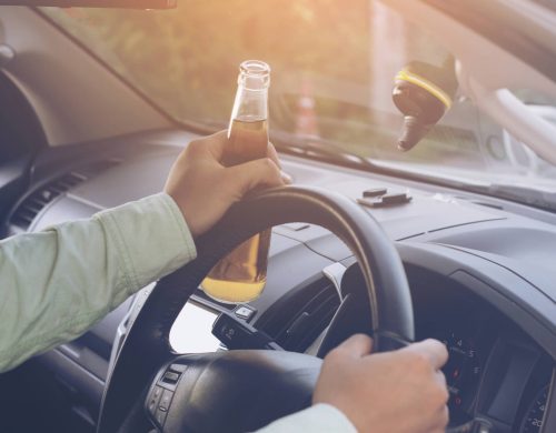Freddie's Bail Bonds - Jacksonville, Florida A man driving a car with a beer bottle in his hand, potentially requiring bail bonds in Jacksonville.